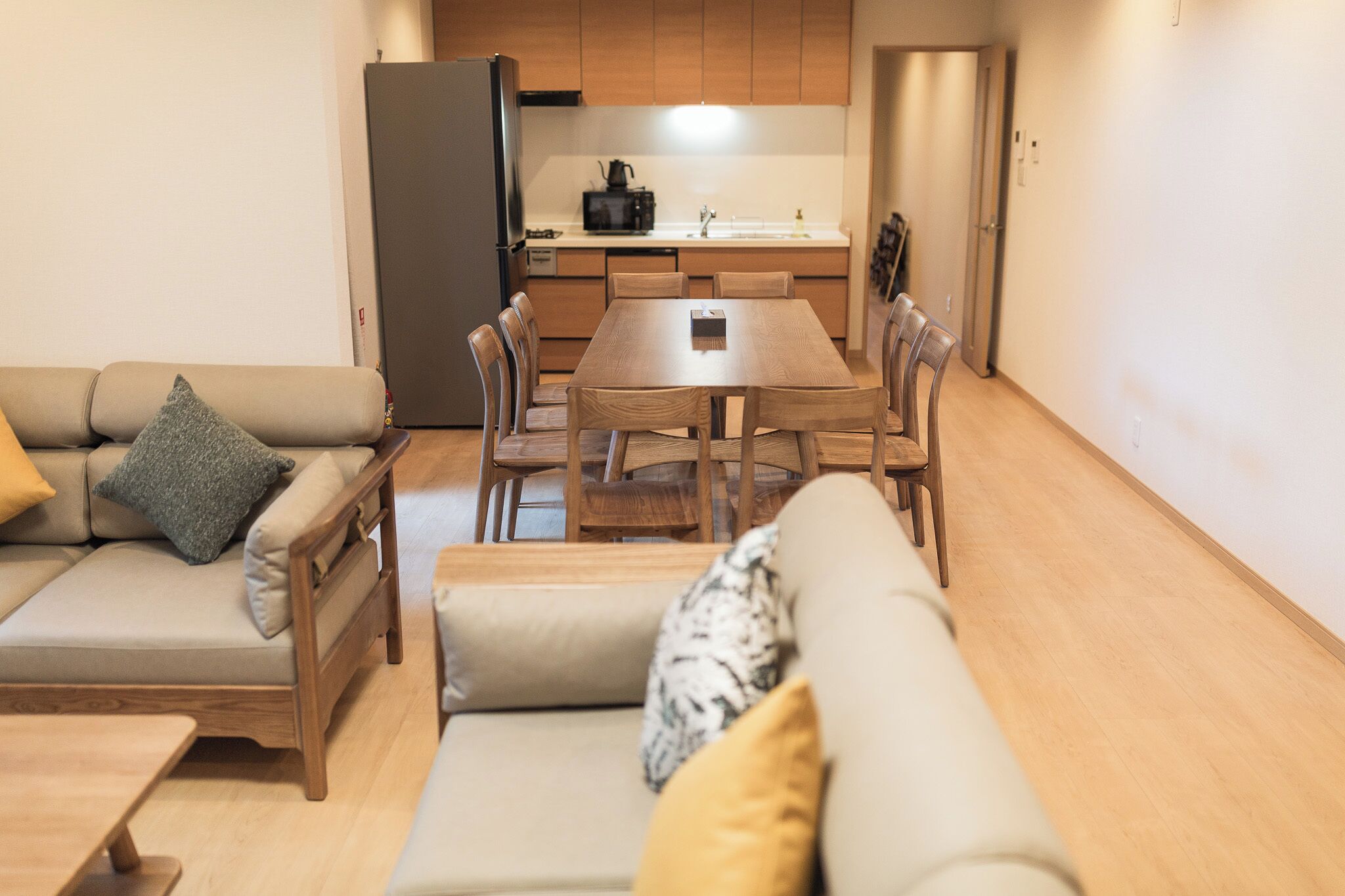 Ein modernes Wohnzimmer mit Sofa, Esstisch mit Stühlen und einer Küchenzeile inklusive Schränken und Geräten.