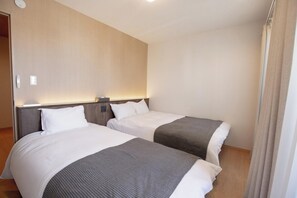 Ett hotellrum med två sängar, var och en med en sänggavel, ett nattduksbord och en lampa.