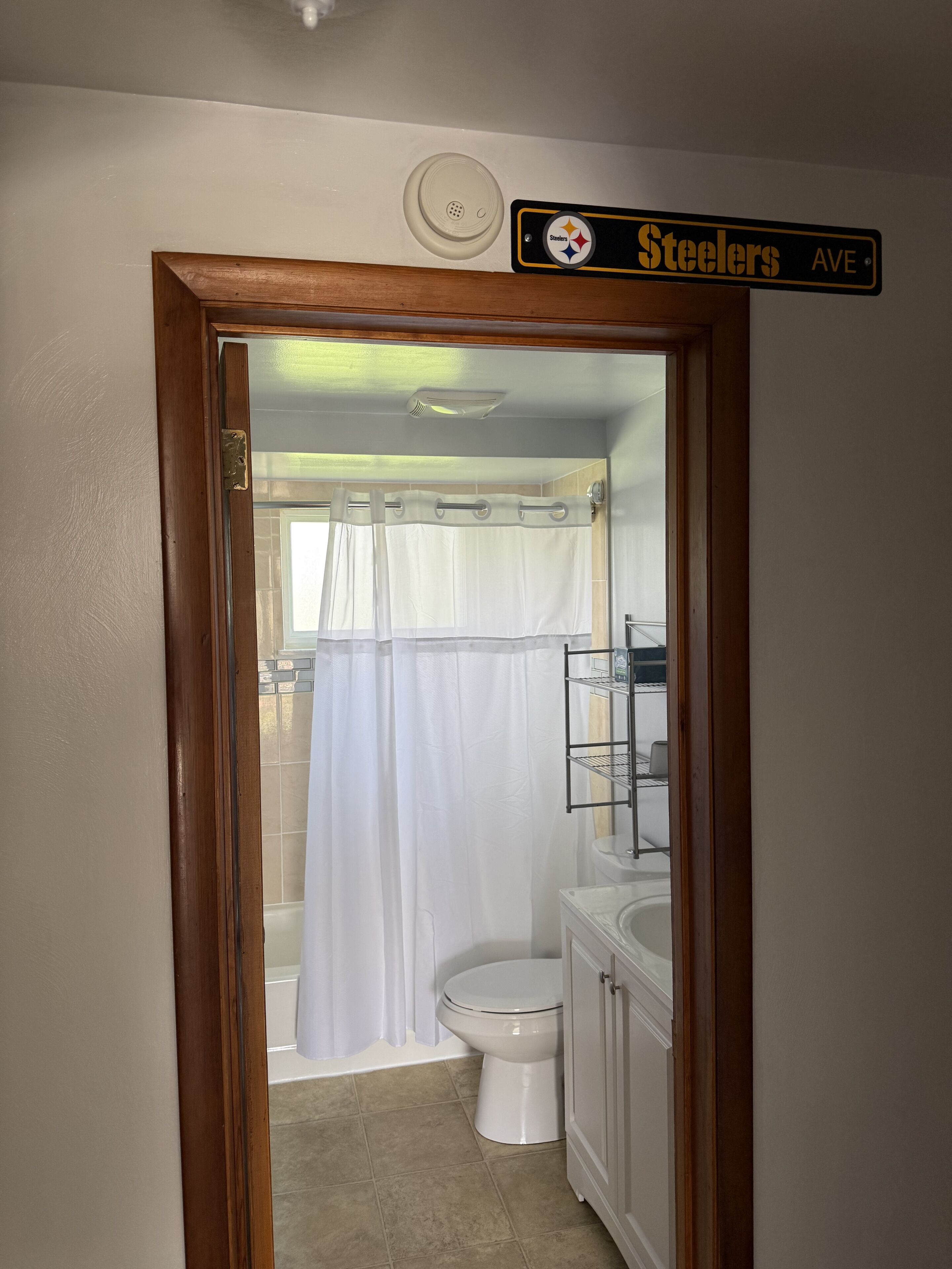 A bathroom with a shower curtain, toilet, and a shelf with toiletries.