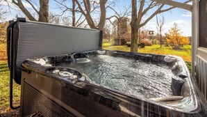 A hot tub with a cover, surrounded by trees and a clear sky.
