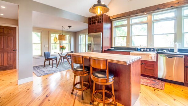 A modern kitchen with a central island, bar stools, a refrigerator, and a dishwasher.