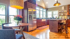 A modern kitchen with a central island, stainless steel appliances, and large windows.