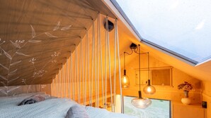 Un dormitorio acogedor con tragaluces, techo de madera y una cama con toallas enrolladas.