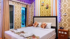 A bedroom with a large bed, a nightstand, and a window with curtains.