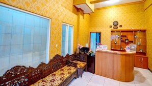 A room with a wooden bench, a reception desk, and patterned wallpaper.