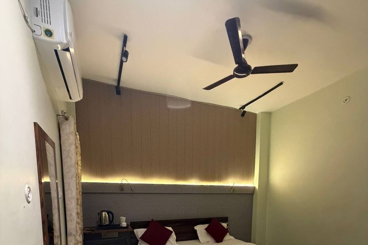 A bedroom with a bed, bedside tables, a ceiling fan, and an air conditioning unit.