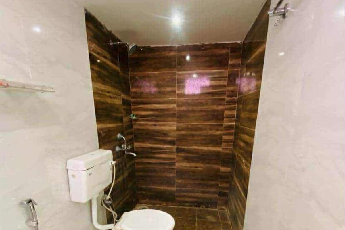 A small bathroom with a toilet, a shower, and a hand dryer.
