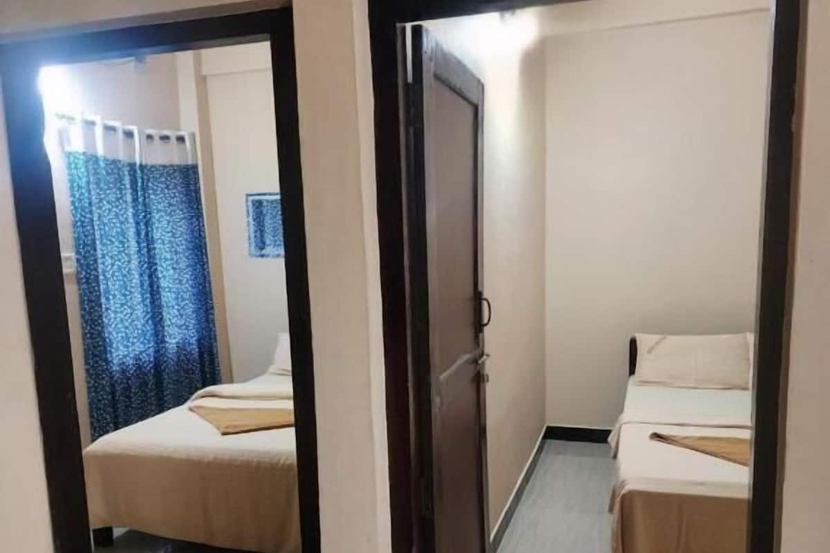 A room with two beds, a mirror, and a door.