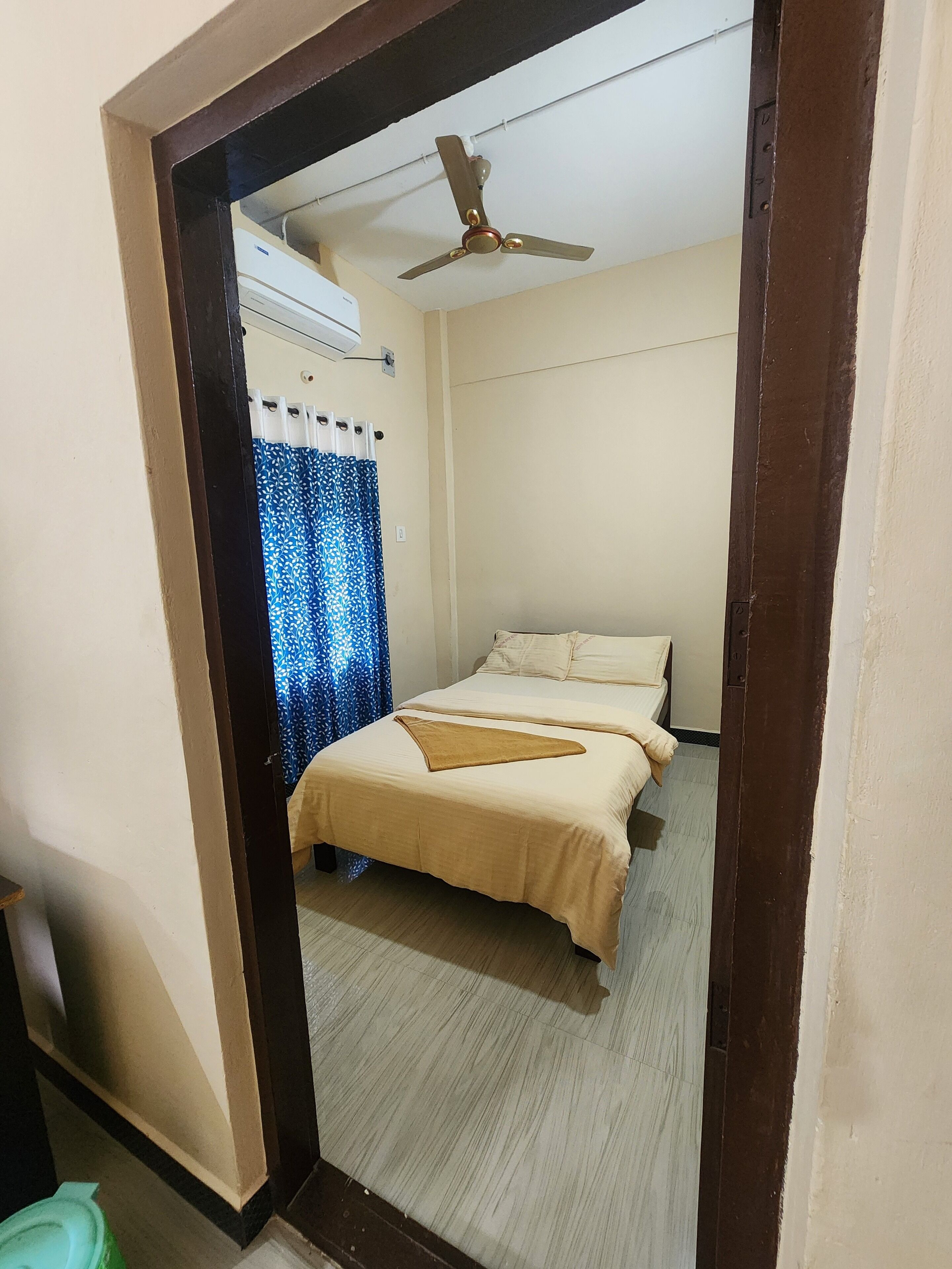 Un dormitorio con cama, ventilador de techo y ventana con cortina.