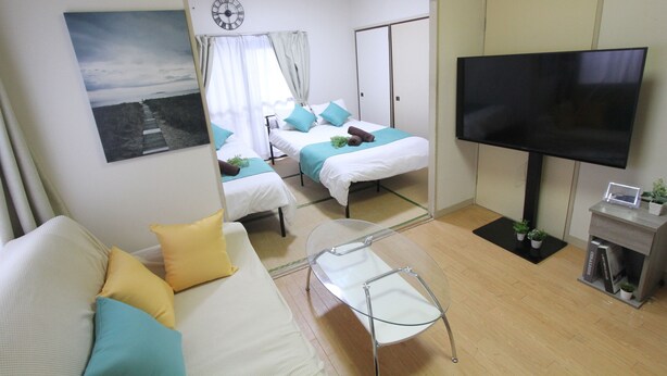 Une chambre d’hôtel avec deux lits, une télévision, un canapé et une table en verre.
