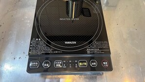 Un appareil de chauffage à induction doté d’un panneau de commande, placé sur une surface métallique.