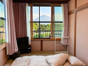 A room with a bed, a TV, a window with a view of a mountain, and a balcony. - Crab and Wagyu Beef Fujisan-tei (Fujikawaguchiko)