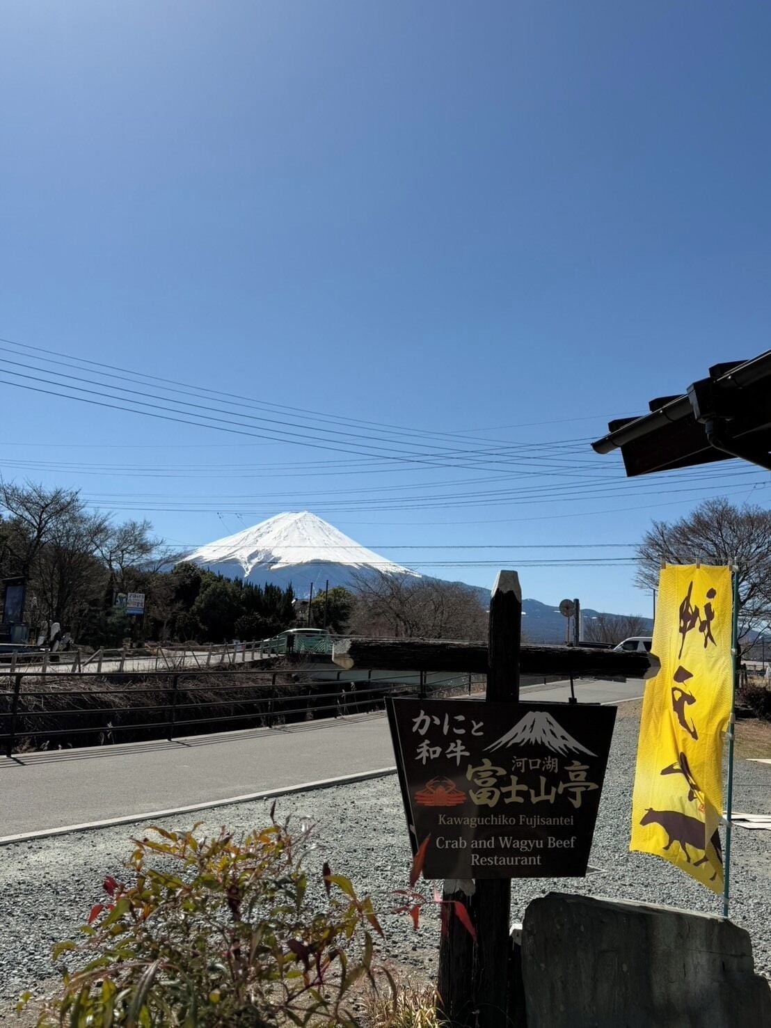 A signboard for Kawaguchiko Fujisantei, a restaurant, with a view of Mount Fuji in the background.