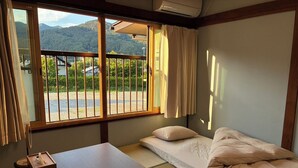 A room with a bed, a table, and a window with a view of a mountain. - Crab and Wagyu Beef Fujisan-tei (Fujikawaguchiko)