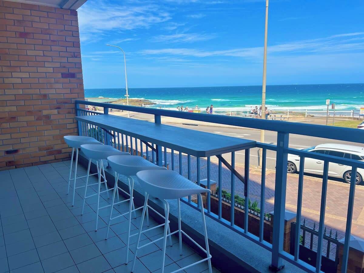 A balcony with a view of the beach and ocean.