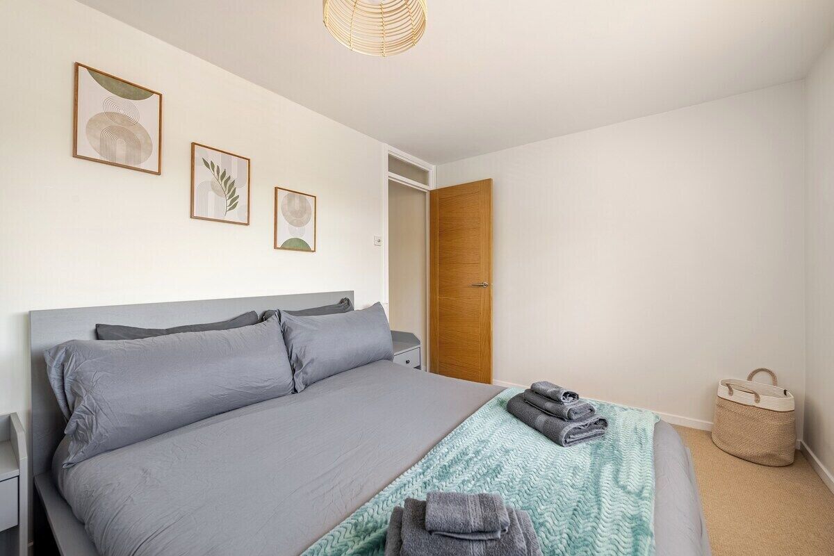 Ein ordentlich eingerichtetes Schlafzimmer mit einem großen Bett, einem Nachttisch, einem Kleiderschrank und einer Deckenleuchte.