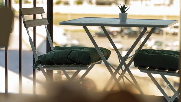 A small outdoor seating area with a table and chairs, a potted plant, and a view of the street. - House Marisa (Casoria)