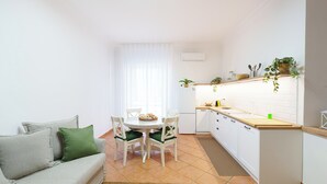 A compact living space with a sofa, dining table, chairs, and a kitchen area. - House Marisa (Casoria)