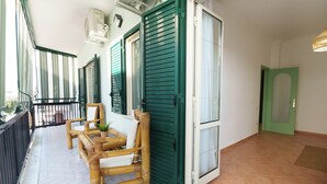 A balcony with a table and chairs, a green door, and a tiled floor. - House Marisa (Casoria)