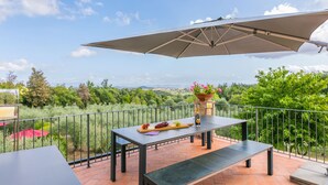 Patio esterno con tavolo, panchina e ombrellone.