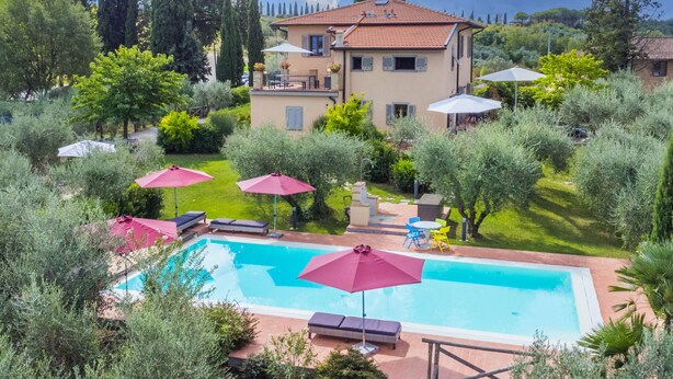 Una villa con piscina, area relax esterna e rigogliosa vegetazione.
