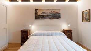 Ein Schlafzimmer mit einem großen Bett, einem Holzkopfende, zwei Nachttischen mit Lampen, einem Bild an der Wand und einer Holzbalkendecke.