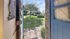 An archway entrance to a property with a welcome sign, a view of a garden, and a blue door with a window. - L'Agapanthe by Interhome (Pornic)