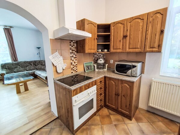 A compact kitchen with wooden cabinets, a built-in oven, a microwave, and a small countertop.