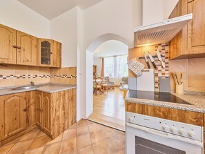 A kitchen with wooden cabinets, a built-in stove, and a dining area with a table and chairs.