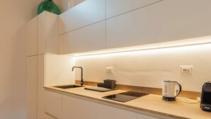 Eine moderne Küche mit weißen Schränken, einer Spüle, einem Wasserkocher und einer Kaffeemaschine.