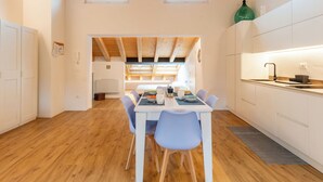 Eine moderne Küche mit Essbereich, Holzbalken und Blick zum Esszimmer.