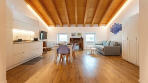 Eine moderne Küche mit Holzbalken, einem Essbereich mit Stühlen, einem Sofa und einem Fernseher.