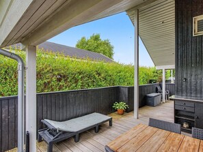 Una terraza al aire libre con un banco, una mesa y una zona de barbacoa.