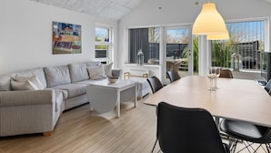 A spacious living area with a high ceiling, a dining table, and a sofa. - "Lanica" - 150m from the sea by Interhome (Mesinge)