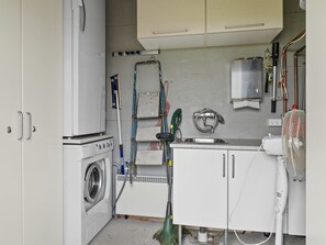 Une petite buanderie équipée d’un lave-linge, d’un étendoir et d’un évier.