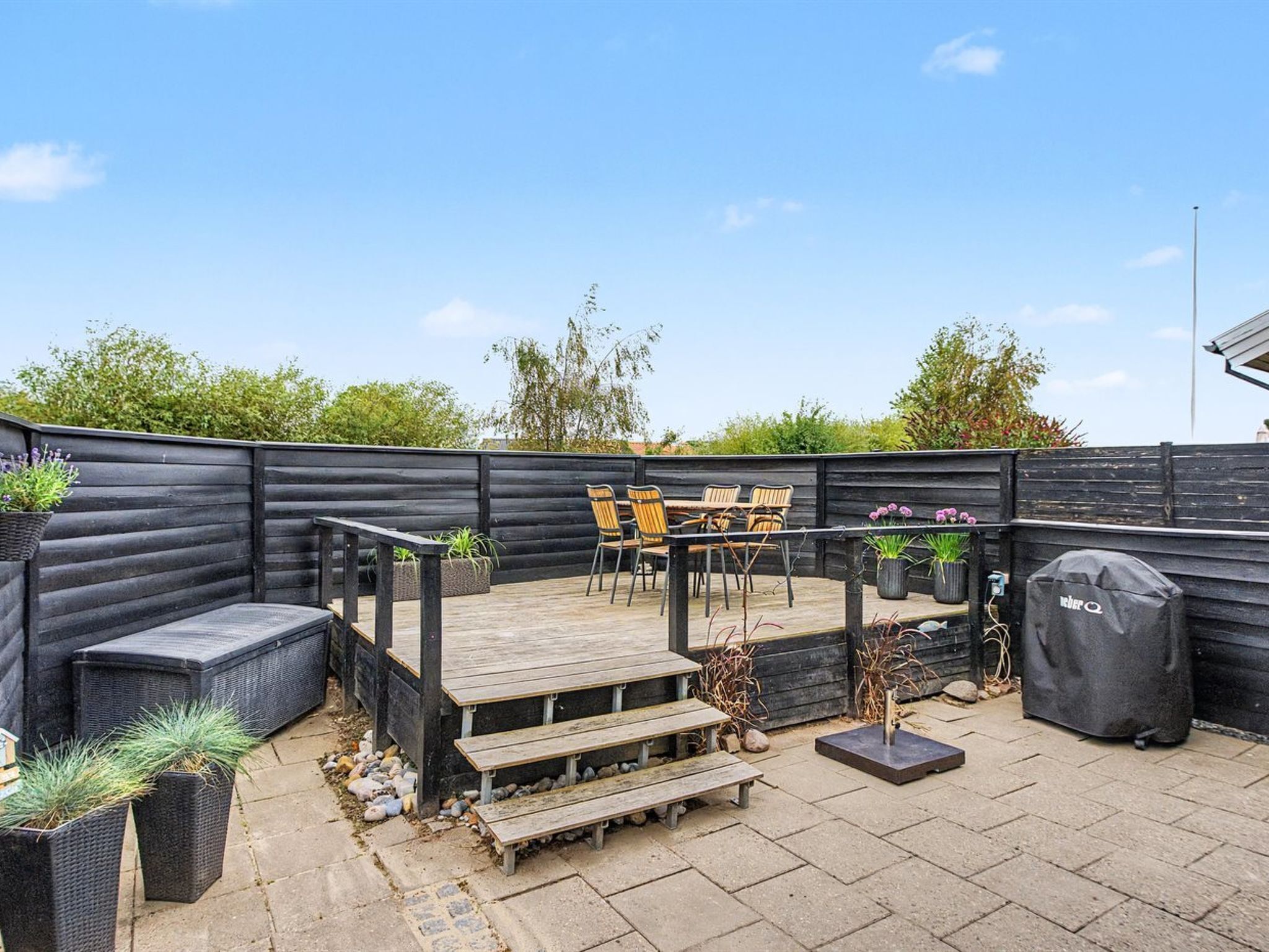 A patio with a wooden deck, outdoor furniture, and potted plants.