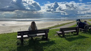 A bench overlooking a beach with a view of the sea and distant land. - De Zeebries by Interhome (Scherpenisse)