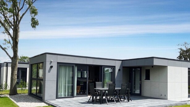 A modern house with a patio, a dining area with chairs, and a large window. - De Zeebries by Interhome (Scherpenisse)
