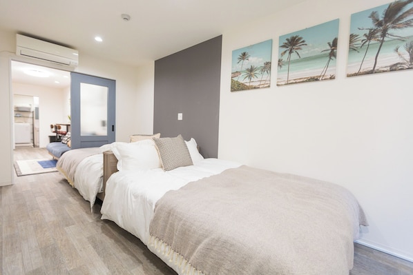 A bedroom with a large bed, a dresser, and a door leading to a bathroom.