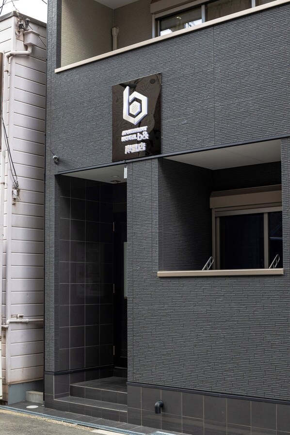 A modern building facade with a prominent logo and a large entrance. - b&Kishinosato (Osaka)