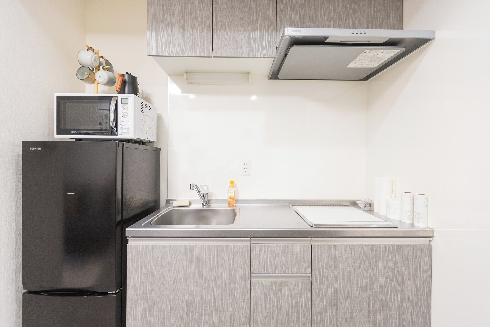 Una cucina compatta con un frigorifero nero, un forno a microonde e un lavello in acciaio inossidabile.