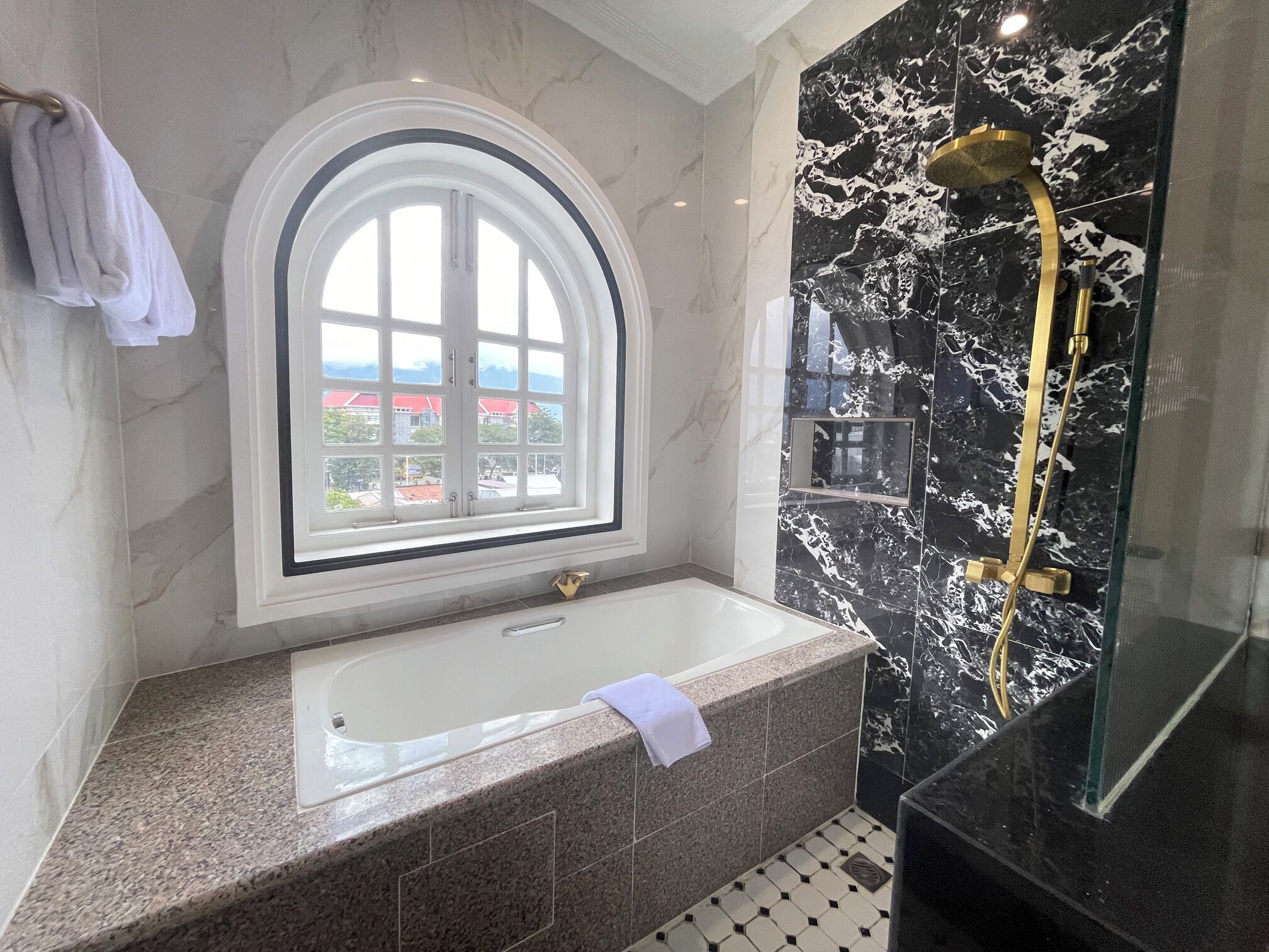 A modern bathroom with a large window, a bathtub, and a shower area.