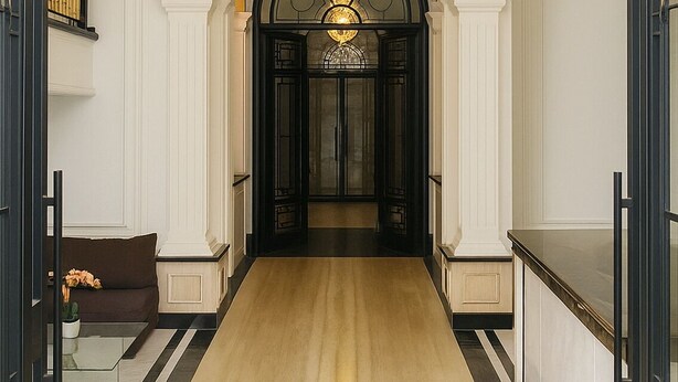 A grand hallway with a large chandelier, white walls, and a wooden floor. - Swiss-Belexpress Palu (Palu)