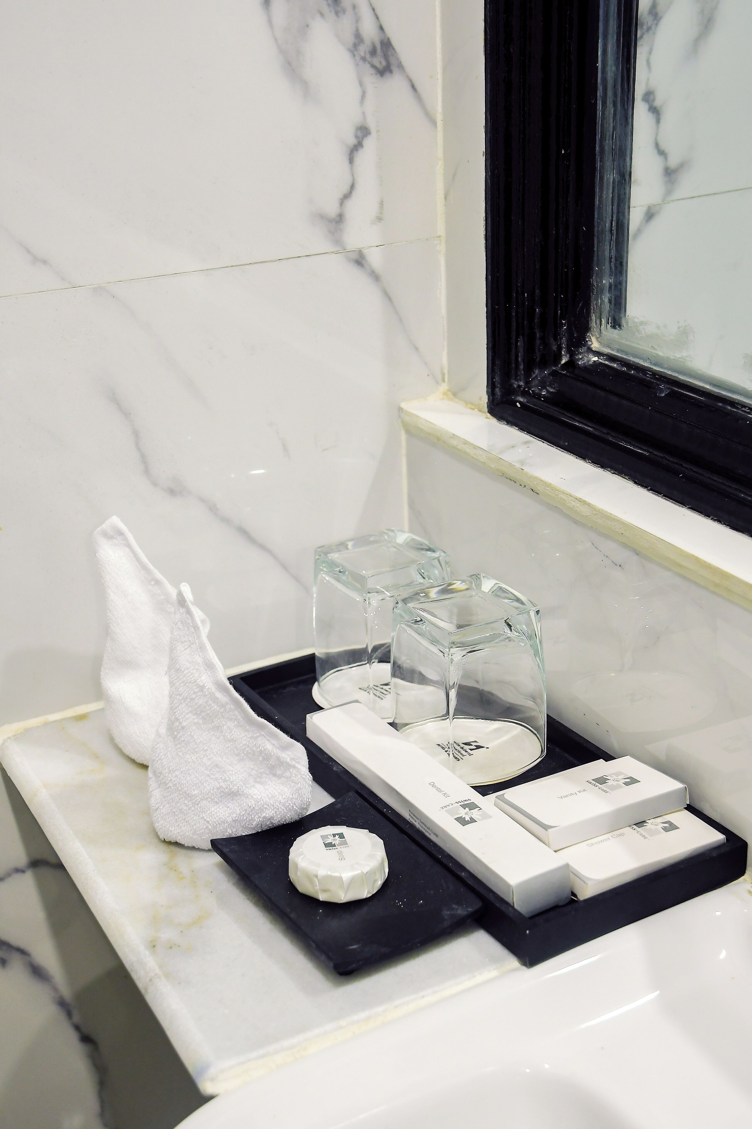 Un lavabo da bagno con piano in marmo, un asciugamano e un vassoio con articoli da toilette.