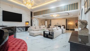 A modern living room with a sectional sofa, a red ottoman, a flat-screen TV, and a marble floor. - Swiss-Belexpress Palu (Palu)