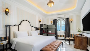 A hotel room with a large bed, a wooden bench, a desk, and a view of the outdoors. - Swiss-Belexpress Palu (Palu)