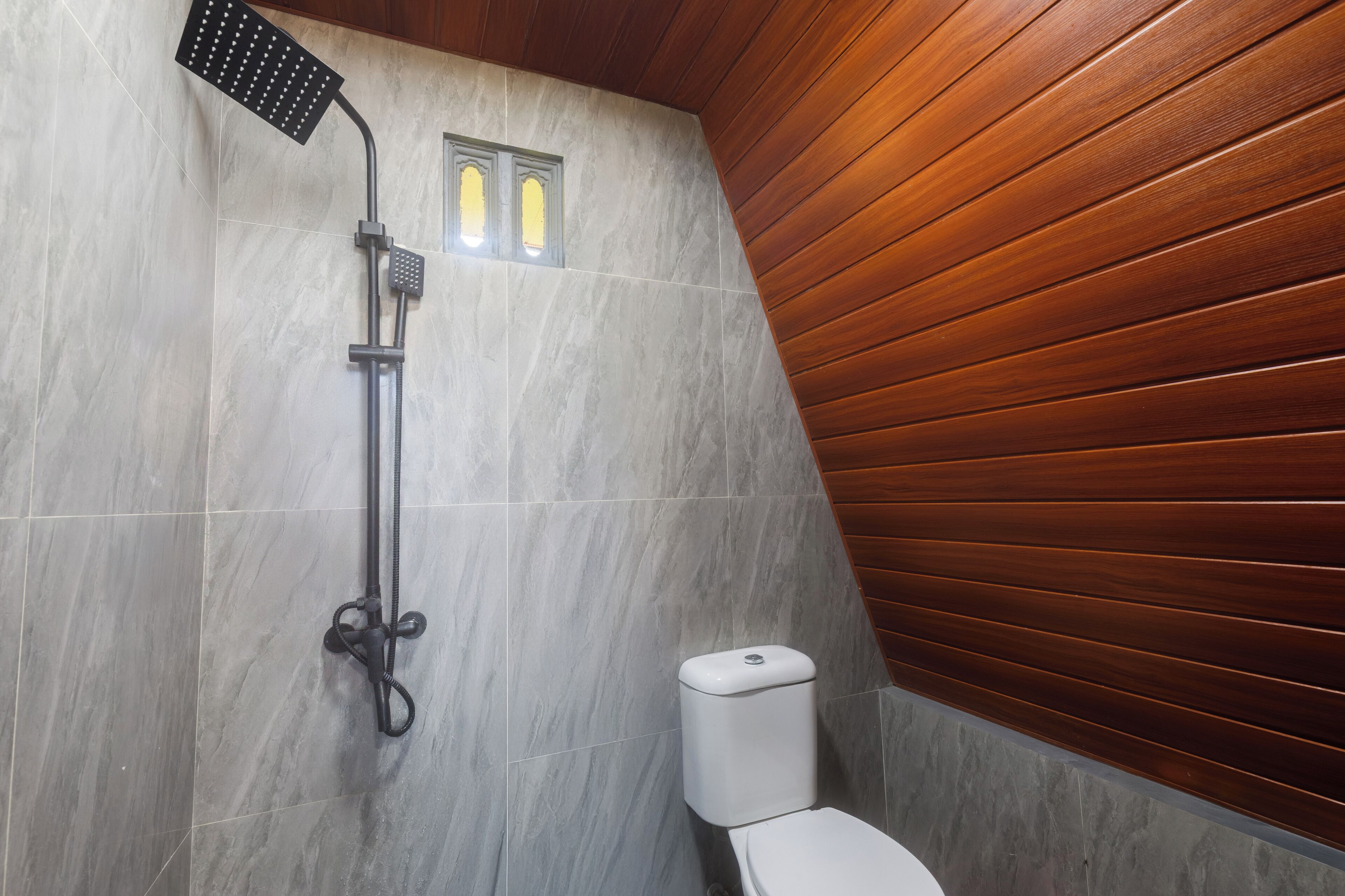 Un baño moderno con ducha, inodoro y una pequeña ventana.