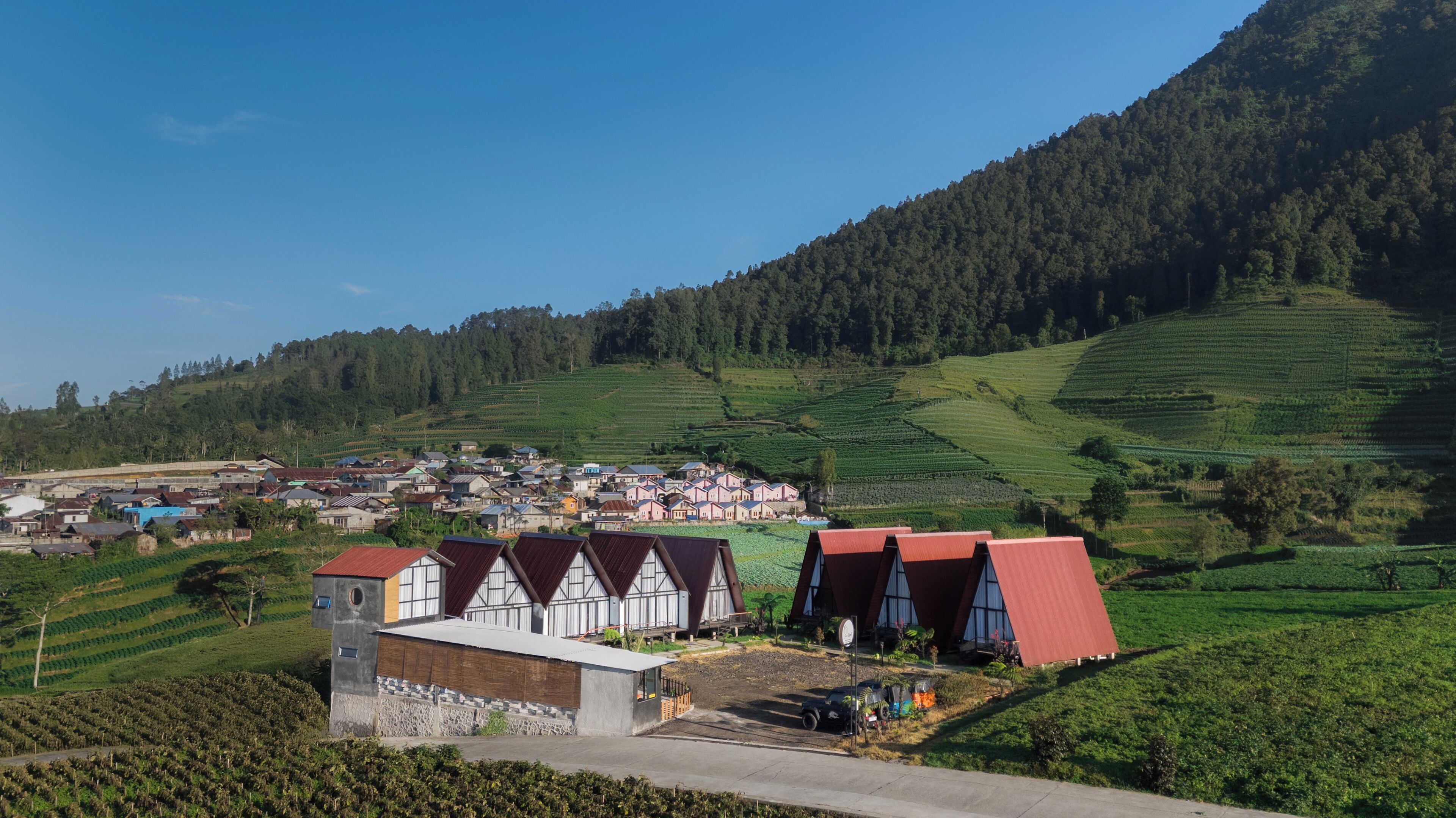 Uma vila rural com casas tradicionais, campos em socalcos e montanhas ao fundo.