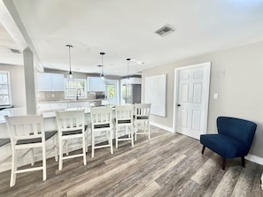 Una cocina moderna con armarios blancos, una isla central con taburetes de bar e iluminación colgante.