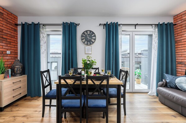 Un comedor con una mesa de madera, sillas azules y un reloj en la pared.